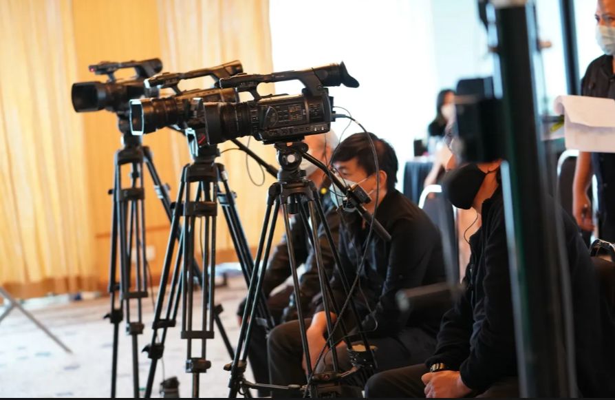 Row of camcorders on tripods with camera operators for multi camera event coverage