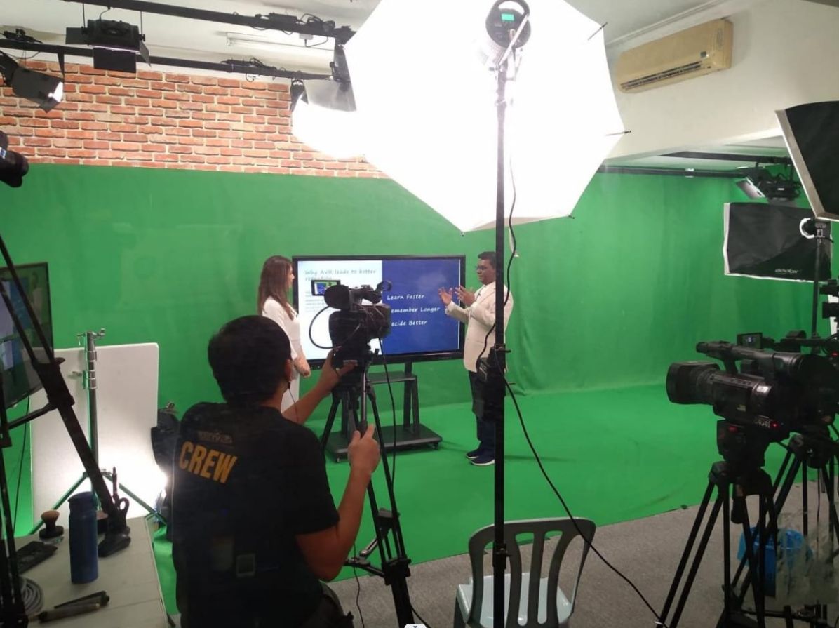 Production crew operating a camera in the green screen studio at May Vision Multimedia